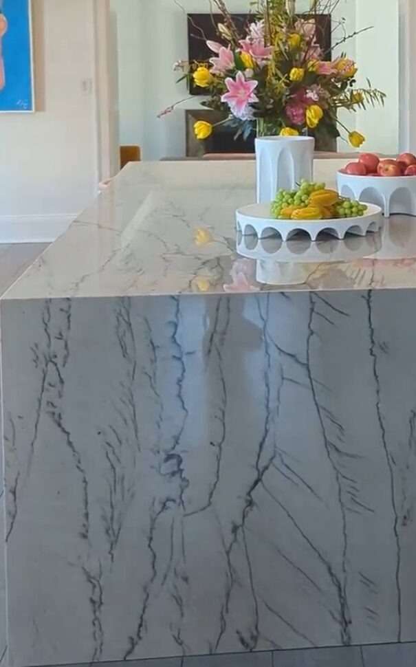 Quartzite kitchen island with mitered waterfall edge — the kind of detail that moves a quote